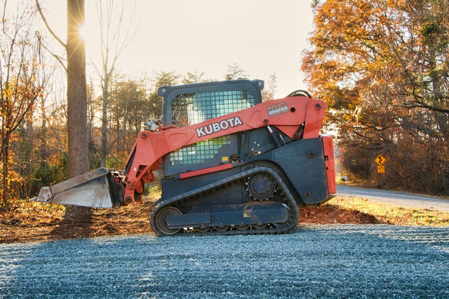 Tracked skid steer working beside a gravel road